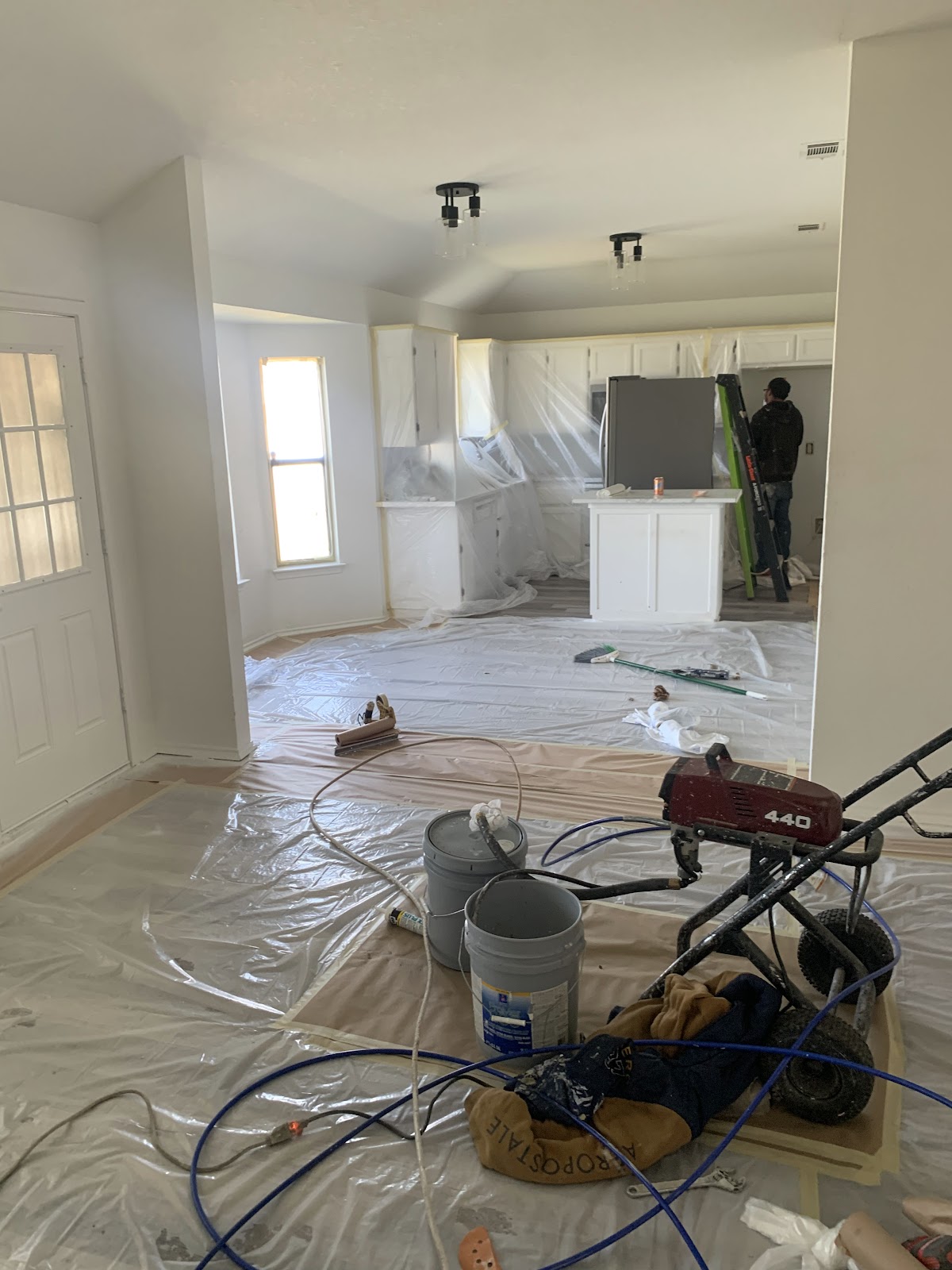 Interior painting in progress: professional drop cloths and spray rig
